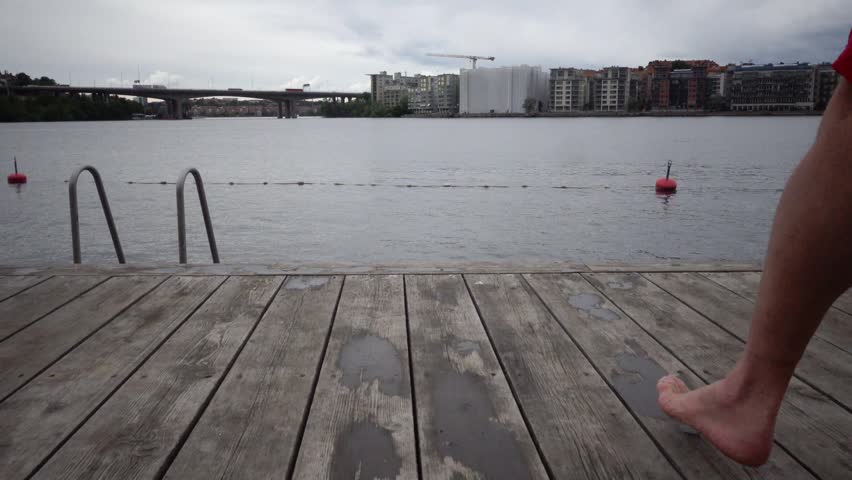 Stockholm, Sweden A man does a plank exercise on a wooden pier on a cloudy rainy day in downtown on Lake Malaren. 