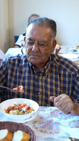 Elderly man in his eighties eating a healthy meal in a nursing home. Close up view of the serene senior enjoying his retirement years