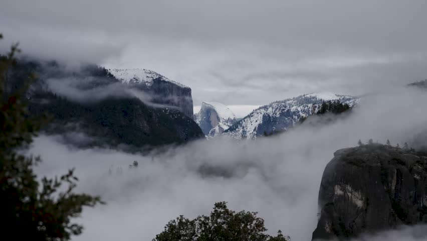 Scenic aerial view of snowy Half Dome and El Capitan with thick fog in Yosemite Valley California