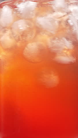 A close-up of a woman stirring fresh strawberry lemonade with berry syrup with a long spoon. Slowly. The chilled berry cocktail is stirred into sparkling water.