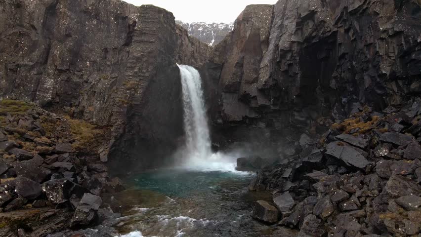 Waterfall cascading down rugged rocky cliff