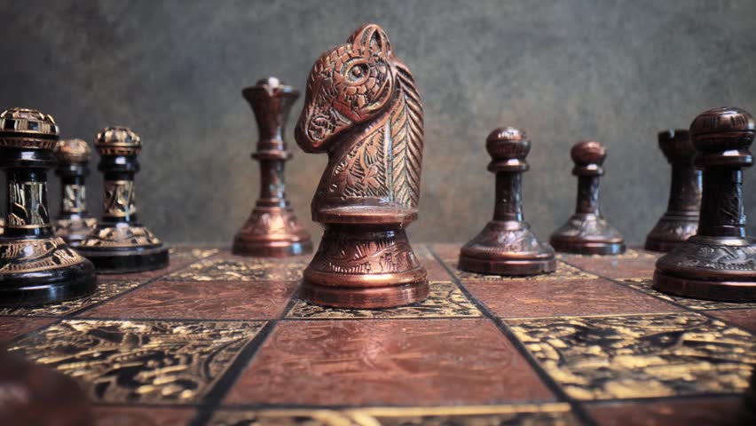 Macro shot showing ornate chess pieces on wooden board during game.