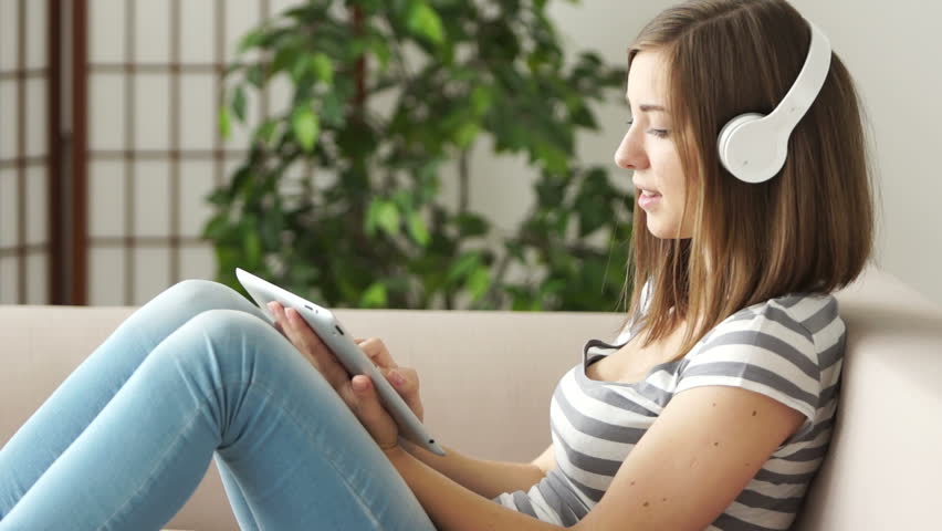 Woman with tablet pc and headphones resting on sofa
