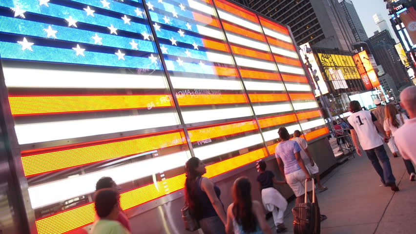 NEW YORK CITY, Circa June, 2013 - People pass the large neon American flag in