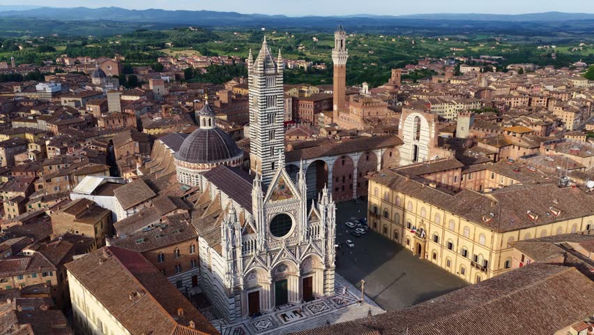 drone orbiting shot of Siena cathedral at sunset, Siena old town skyline, tourist city in Tuscany, travel in Tuscany, Italy, aerial view of Renaissance cathedral in Siena