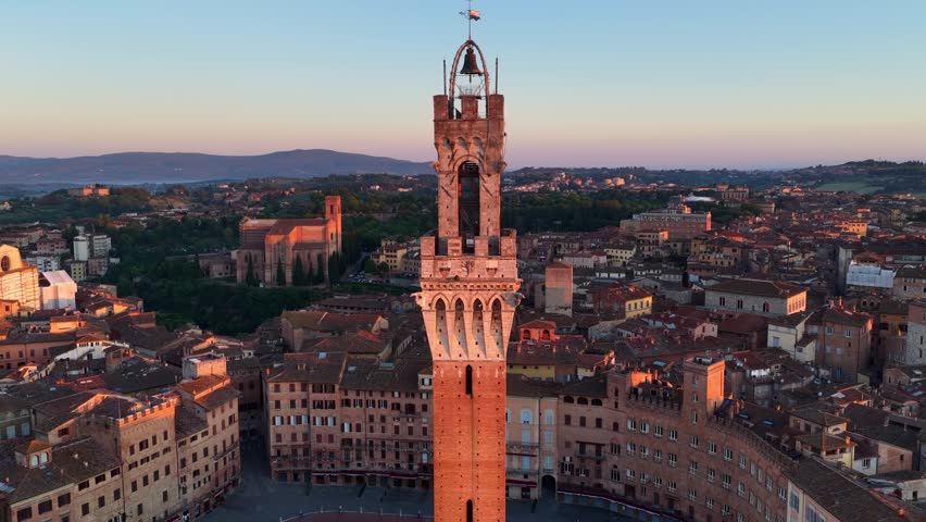 Orbiting drone shot of Torre del Mangia at sunrise in Siena, Tuscany, historic Italian city of Siena aerial view at sunrise, tourism in Tuscany, Italy