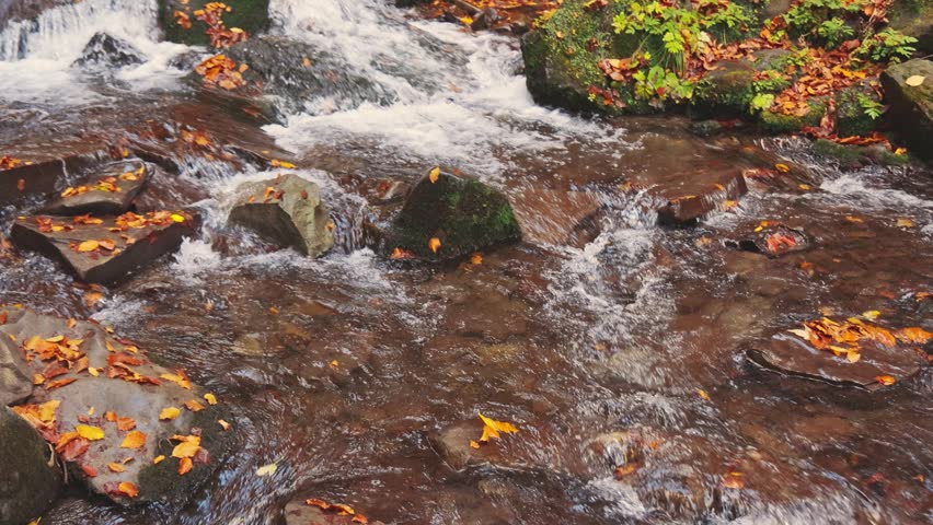 Waterfall falling down mountain slope in autumn forest
