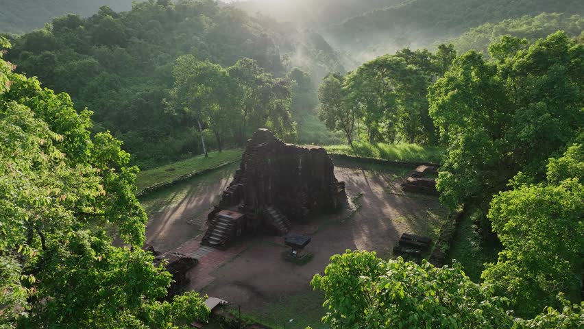Morning sunlight and mist drift above historic temple ruins at My Son Sanctuary in Vietnam.