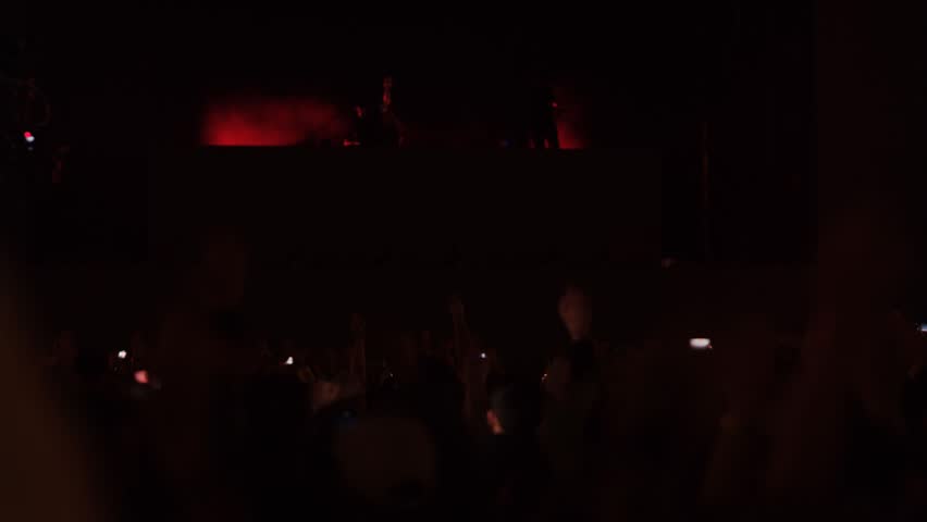 Large number of cheering and dancing people at concert in front of stage with raised hands chanting to rhythm of music and song. Night party with large number of music fans. entertainment nightlife