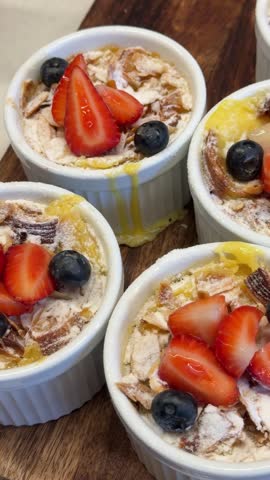 Five white ceramic cups with healthy chia pudding and oatmeal topped with strawberries and blueberries in restaurant display