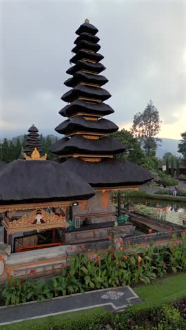 Aerial view of iconic Ulun Danu Beratan Temple surrounded by water and gardens on Lake Beratan, Bali. Traditional Balinese architecture in a peaceful mountain setting.