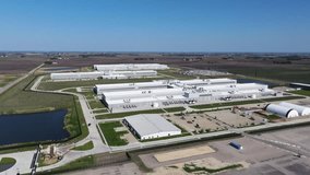 Forward drone shot above a large hyperscale data center campus moving toward a prominent power substation surrounded by agricultural land. - Powered by Shutterstock - Get 15% off with code: PIKWIZARD15