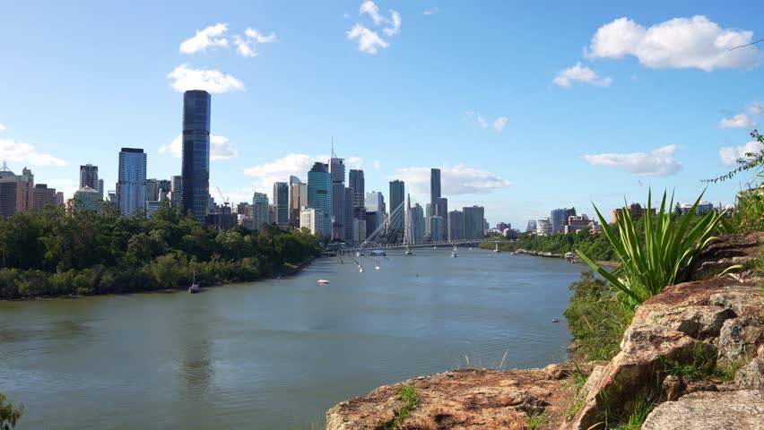 View from Kangaroo Point Cliff of the Brisbane downtown cityscape under a blue sky, with the bridge spanning the river.