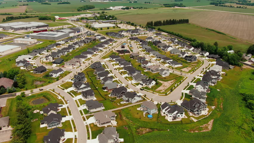 Circling Aerial Establishing shot of modern suburban neighborhood surrounded by farmland with curving streets, Waunakee, Wisconsin