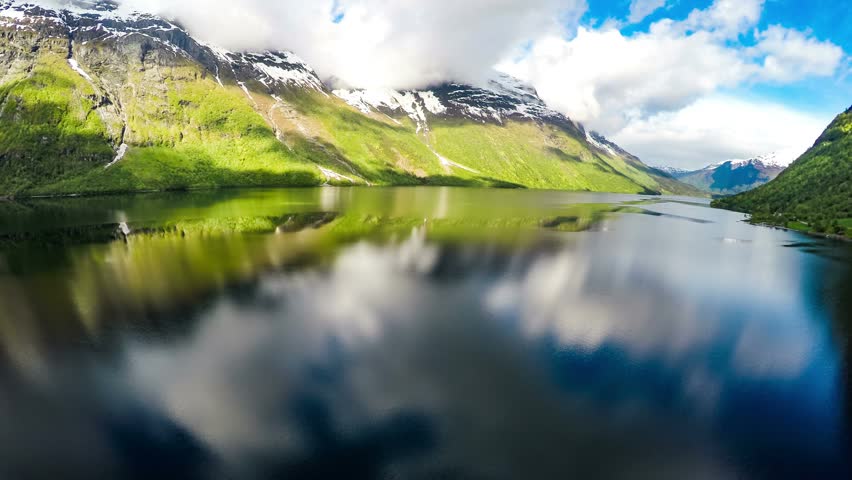 Majestic mountains, calm lake, scenic nature, aerial view, cloudy sky.
