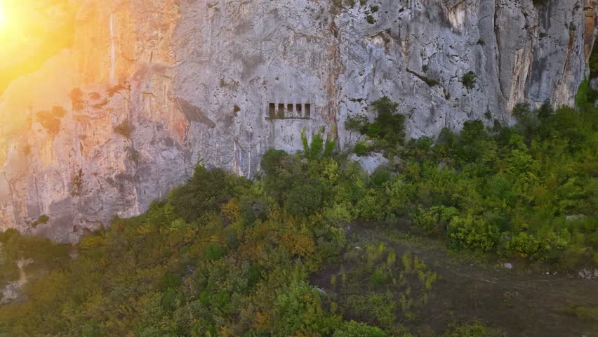 4K 60fps cinematic drone footage smoothly pulling back from a closer view to a wide establishing shot of a natural landscape during sunset. Warm golden light spreads across the scene, creating a dramatic and atmospheric aerial view.