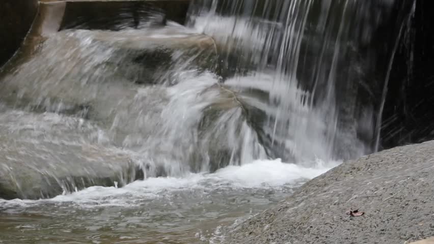 Video A small man-made waterfall or weir cascading clear water over smooth rocks into a splashing pool below