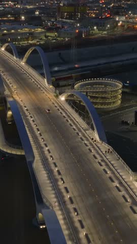 High angle view of richly illuminated 6th Street Viaduct. Tilt up reveal evening cityscape. Los Angeles, California, USA