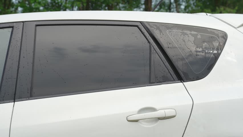 A man washes the car windows with a cloth before applying an anti-rain coating.