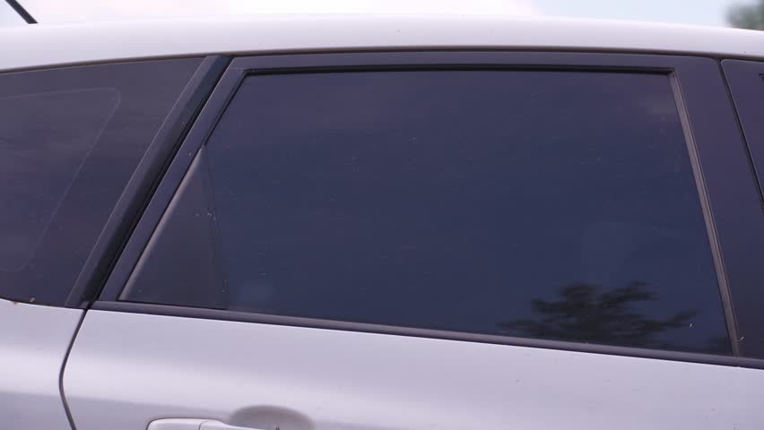 A man washes the car windows with a cloth before applying an anti-rain coating.