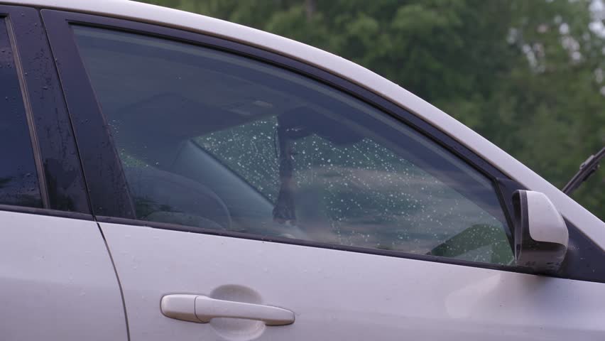 A man washes the car windows with a cloth before applying an anti-rain coating.
