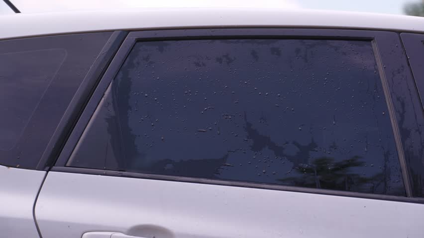 A man washes the car windows with a cloth before applying an anti-rain coating.