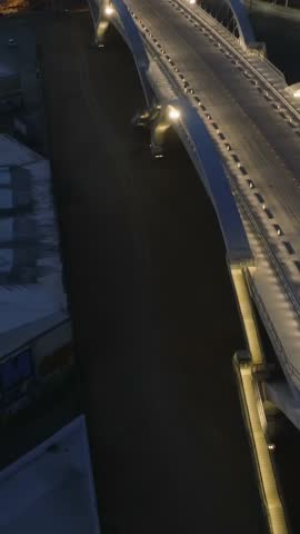 Forwards fly above illuminated road bridge with concrete arches. Aerial night shot of 6th Street Viaduct. Los Angeles, California, USA