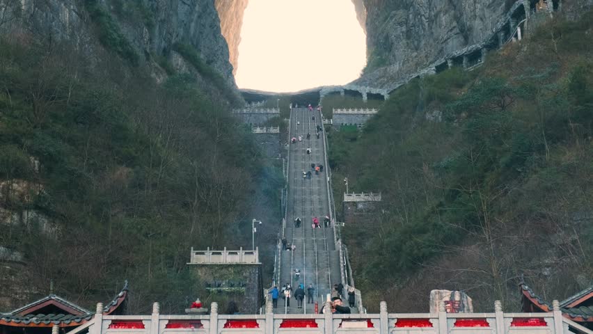 Natural stone arch with long staircase between towering cliffs at sunrise.in Tianmen Mountain National Forest Park, Zhangjiajie, Hunan, China. Tianmenshan cave with 999 steps