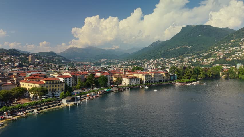 Scenic waterfront of Lugano in Switzerland with beautiful historical buildings and boat docks. Aerial view of luxury resort town at the alpine lake foot. Bay of Lugano lake 