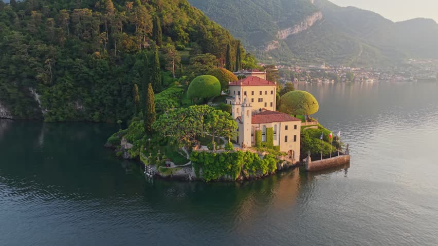 Picturesque Villa del Balbianello standing on green cape in Italy. Aerial view of Villa del Balbianello on Lake Como during golden hour. Iconic architecture of Villa del Balbianello