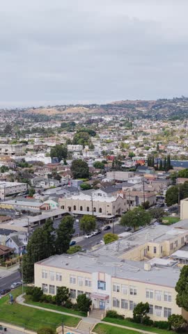 Urban landscape revealing Los Angeles neighborhoods, residential houses, busy streets, local school buildings with rolling hills visible on the horizon