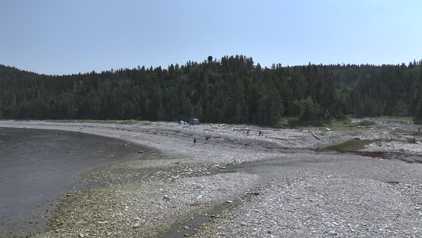 People walks in a Dirt and Stone Road Between the Forest and the River near the Waterfall Known as "Chute à Boule" in Anticosti Island, Quebec, Canada