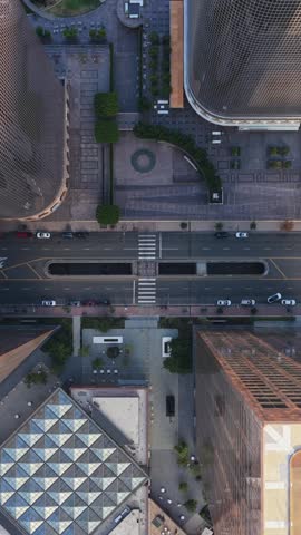 Top down fly over of an urban street in Downtown Los Angeles showing modern city architecture and skyscrapers with moving traffic in the financial district