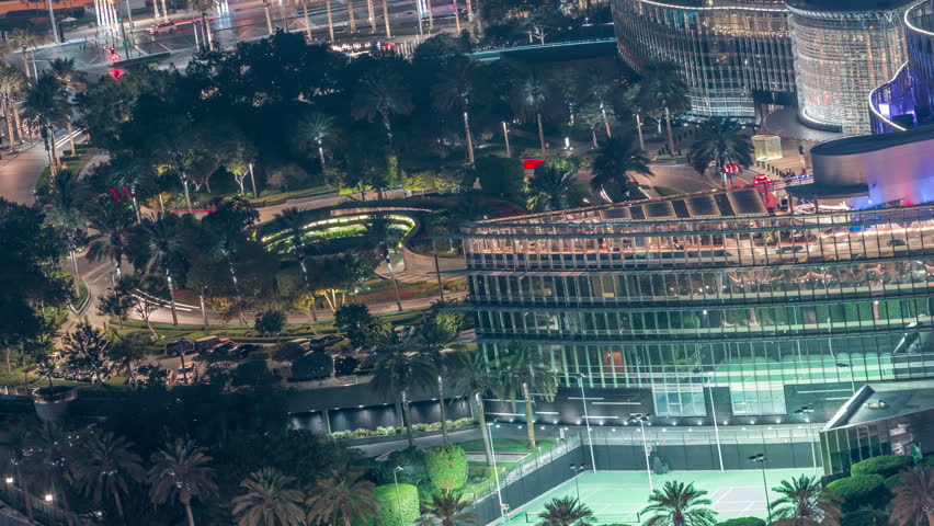 Illuminated urban park timelapse footage recorded during night within Downtown Dubai. The extensive pedestrian walkways glow warmly beneath the surrounding skyscraper peaks.