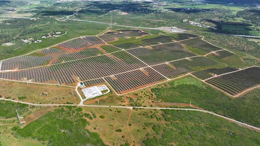 A solar power plant is visible with rows of photovoltaic panels positioned on land. The facility contributes to sustainable electricity generation.