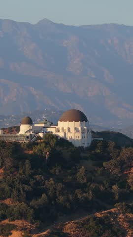 Griffith Observatory perched on a hill with San Gabriel Mountains in background during sunrise in Los Angeles, California showing amazing science location