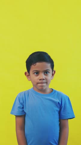 Adorable young boy showing pure joy and excitement after receiving a small red present. His cheerful expression lights up the yellow background