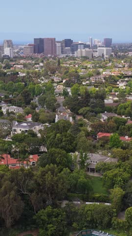 Affluent Beverly Hills neighborhood with luxury homes and mansions revealing Century City skyline in Los Angeles, California during day
