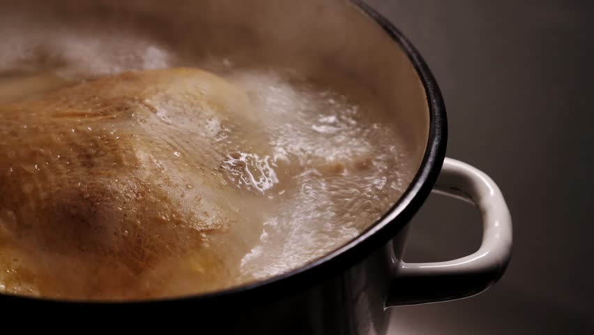 Chicken is boiling in a metal pot.