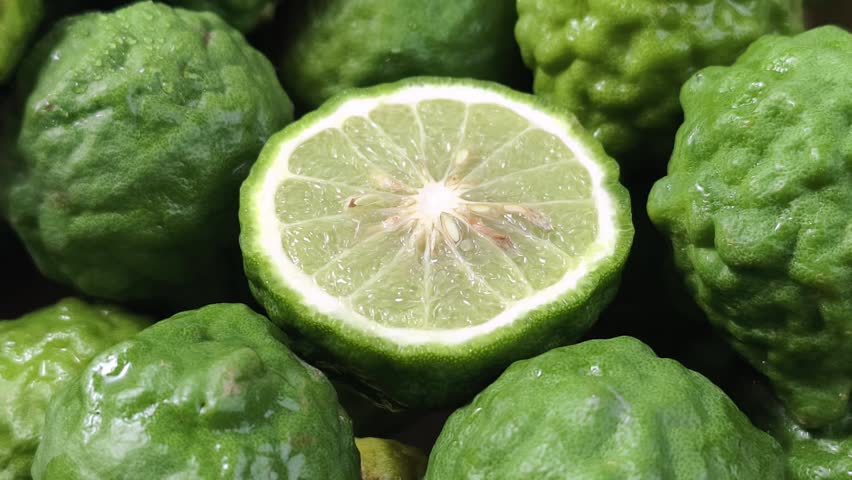 A close-up of a sliced bergamot surrounded by whole ones