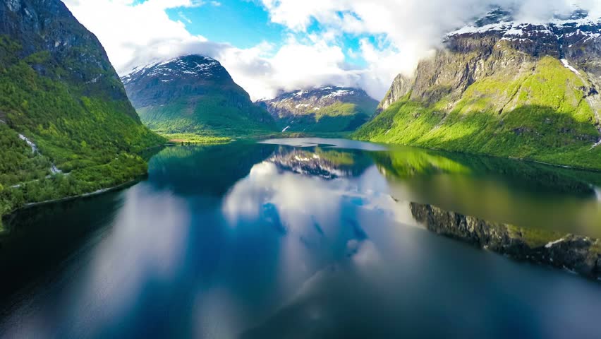 Aerial view over tranquil lake reflecting sky and mountains.