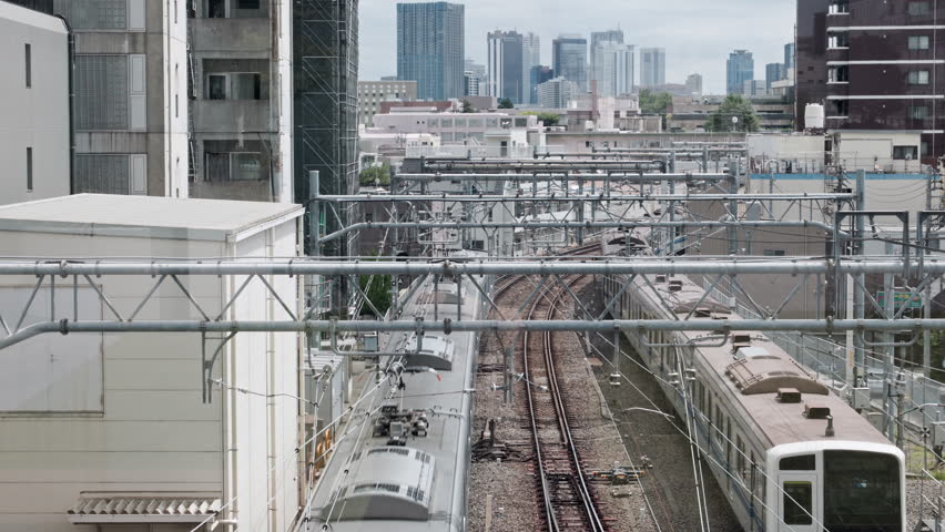 Tokyo Scene  :  Metropolitan Commuter Train Running on Tracks Surrounded by High-Rises and Numerous Overhead Wires and Poles  |  Ikebukuro, Tokyo, Japan