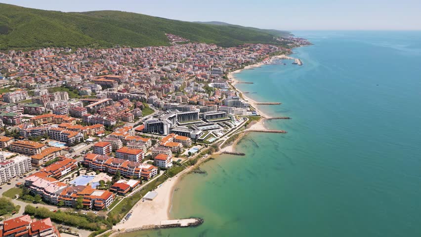 Beautiful panoramic aerial view of Sveti Vlas resort city with red roof hotels, turquoise Black Sea coastline and green Balkan mountains in Bulgaria.