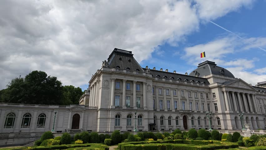 Brussels Royal Palace. 4K video shot of the grand Royal Palace of Brussels, featuring neoclassical white architecture, manicured green garden hedges, and the Belgian flag waving. Belgium landmark