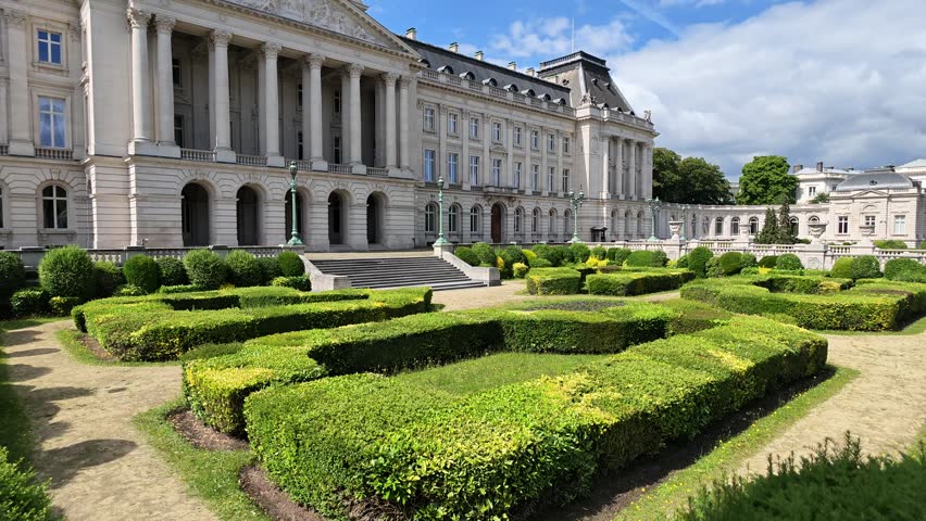 Brussels Royal Palace. 4K video shot of the grand Royal Palace of Brussels, featuring neoclassical white architecture, manicured green garden hedges, and the Belgian flag waving. Belgium landmark