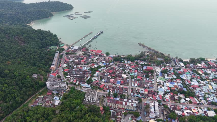 Drone captures coastal town, piers, houses and jungle near Teluk Bahang, Malaysia.