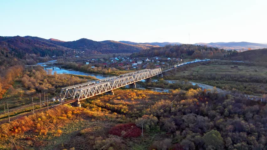 Railroad bridge over river in highland with colorful trees
