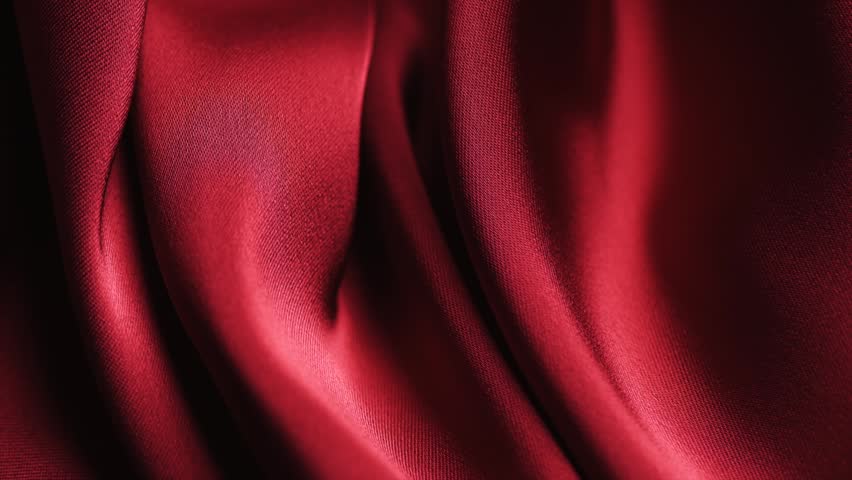 Satin backdrop, red color silk background, texture of beautiful red satin fabric close-up. Abstract smooth backdrop. Rotating, slow motion.