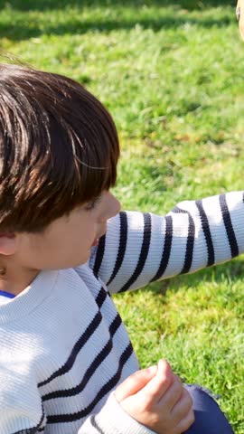 Young boy experiencing his first contact with a cute baby goat held in a woman