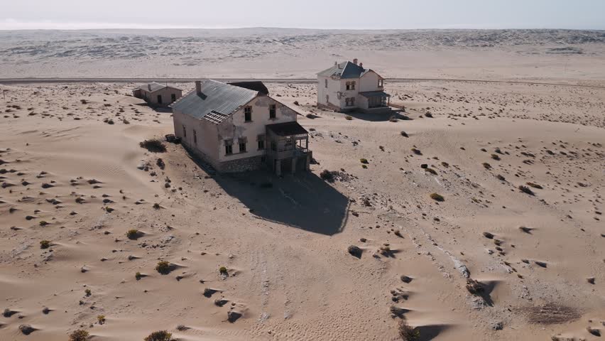 Aerial view of abandoned kolmanskop ghost town houses being swallowed by sand dunes in the namib desert of namibia.